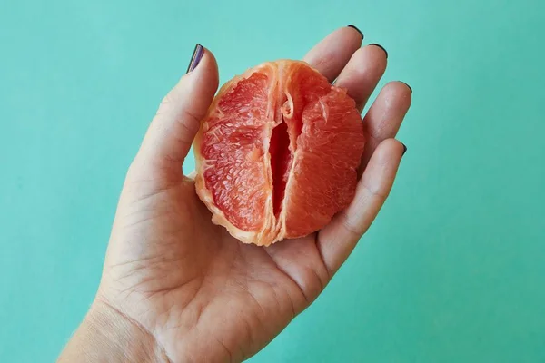 Mão segurando uma toranja para representar uma vagina