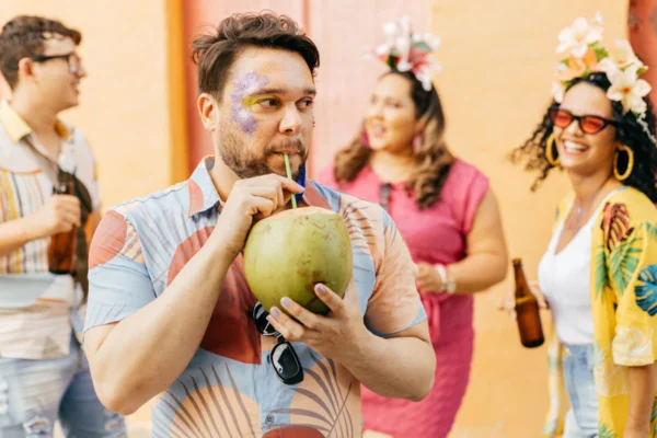 Imagem colorida de folião tomando água de coco