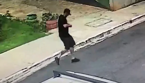 Imagem colorida de homem com camiseta, bermuda e boné pretos mexendo em objeto na altura do peito - Metrópoles