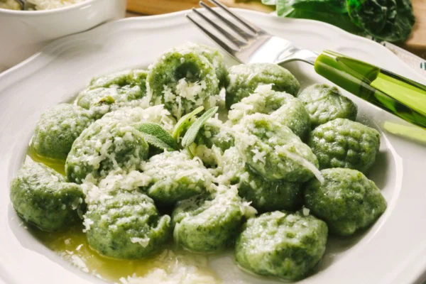 Nhoque verde servido em prato branco