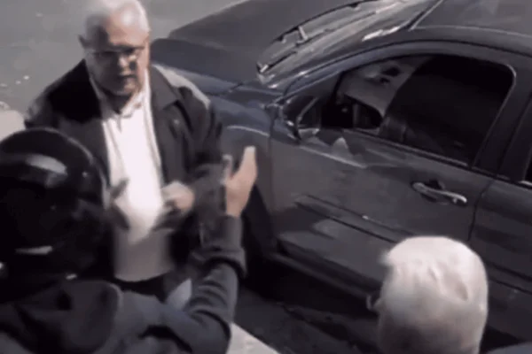 Imagem colorida de um homem de capacete tentando assaltar outros dois homens de cabelos grisalhos que pertenciam a uma igreja - Metrópoles