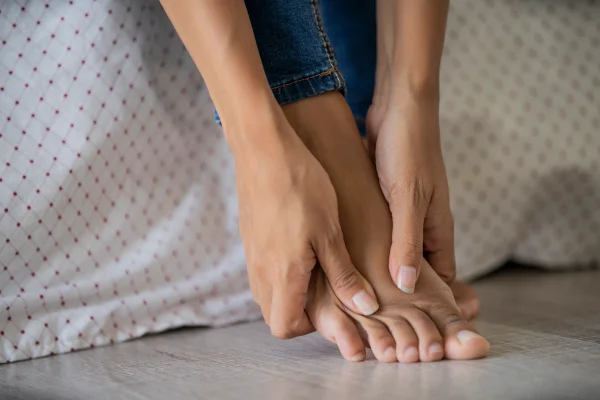 Imagem mostra mãos de mulher com unhas compridas massageando um dos pés - Metrópoles