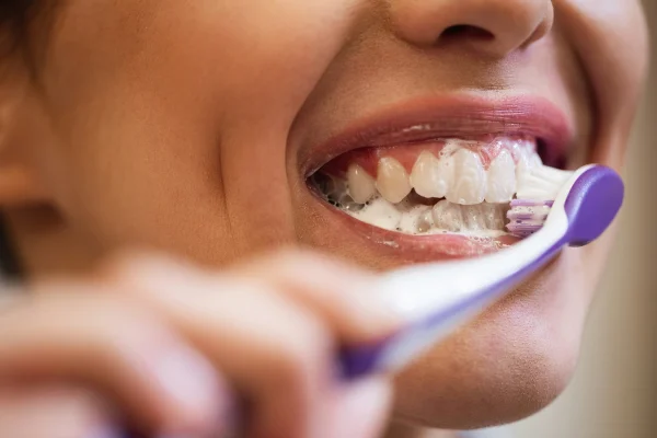 Close-up de mulher usando escova de dentes enquanto limpa os dentes