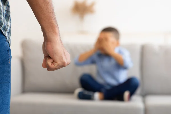 Abuso infantil. Pai negro irreconhecível cerrando o punho, pronto para bater em filho pequeno assustado, ameaçando menino na sala de estar de casa. Violência doméstica contra criança. Metrópoles