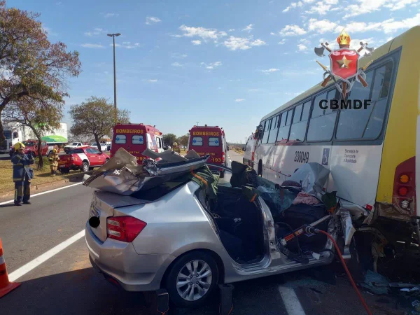 Imagem colorida de acidente em que umm carro prata bateu na traseira de ônibus amarelo
