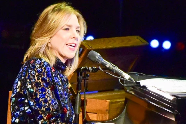 Foto colorida da cantora Diana Krall de roupa florida tocando piano - Metrópoles