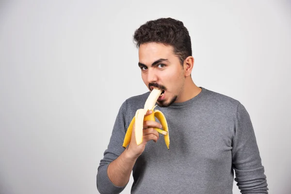 Foto colorida de homem comendo banana