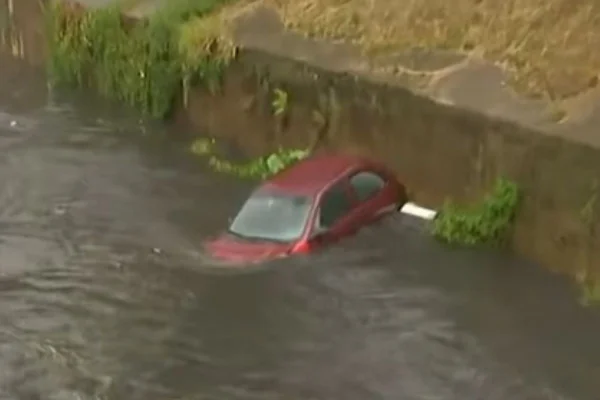 Carro vermelho imerso em córrego - Metrópoles