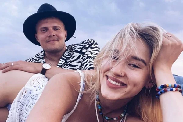 Casal deitado na praia juntos sorrindo - Metrópoles