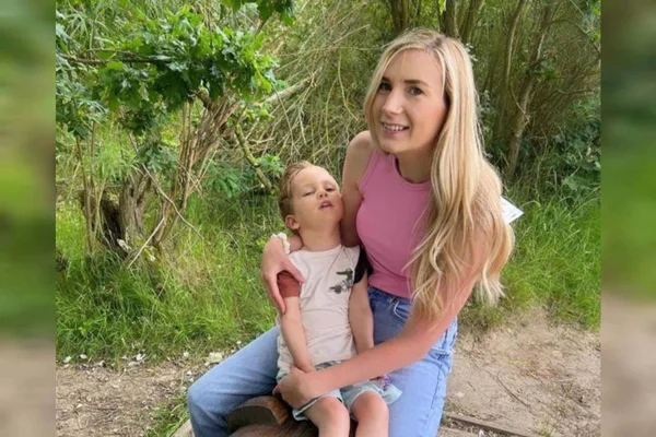 Foto mostra Kate, uma mulher loira, com seu filho Joey, de 3 anos, no colo, Ele tem o corpo debilitado por leucodistrofia metacromática LDM - Metrópoles