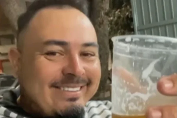 Imagem colorida de homem segurando copo. Metrópoles
