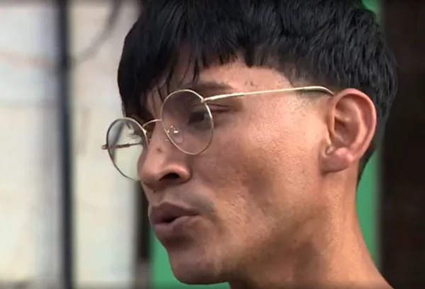 Foto colorida mostra rosto de homem de óculos, cabelo escuro e franja