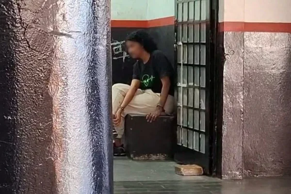 Imagem colorida mostra mulher sentada em banco de delegacia - Metrópoles