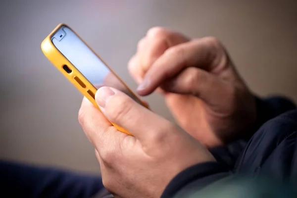 Mãos segurando celular e tocando na tela - Metrópoles