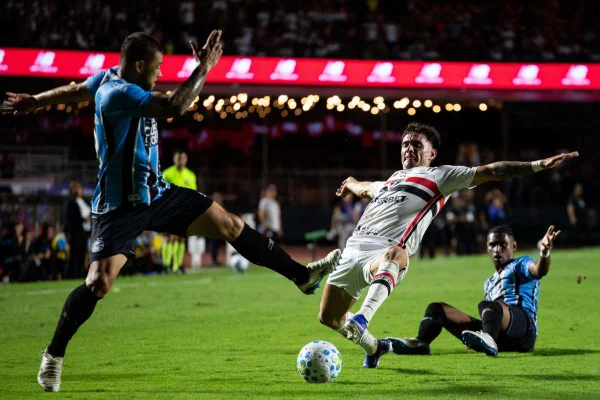 Jogadores de Grêmio e São Paulo disputam a bola durante partida.
