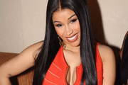 Cardi B posa sorridente de cabelos soltos e look vermelho