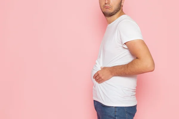 Homem de perfil apertando a barriga - Metrópoles