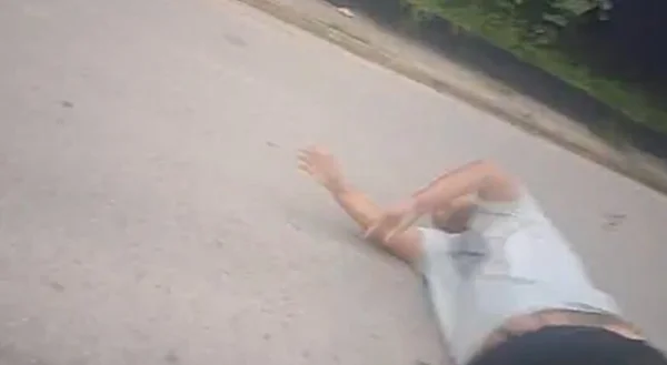 Imagem colorida mostra homem de camiseta branca caído na rua; ele é um policial civil que foi nocauteado por um jovem após uma discussão na frente de uma delegacia - Metrópoles