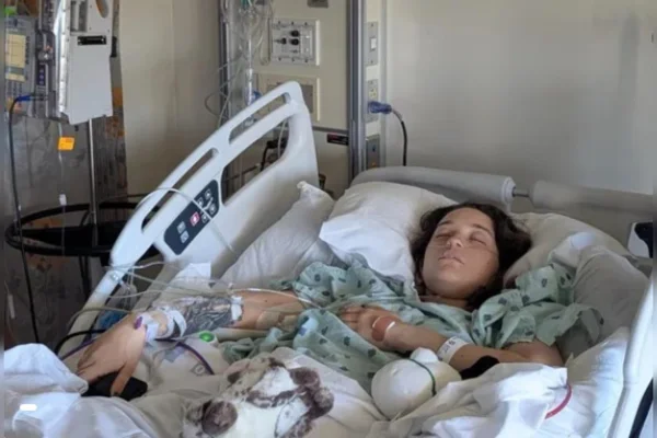 Foto colorida de jovem deitada em uma cama de hospital conectada a tubos - Metrópoles.