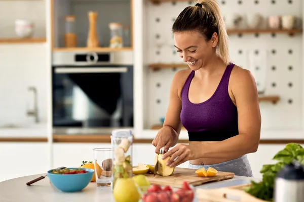 Foto colorida de mulher cortando frutas em uma cozinha - Metrópoles - ressaca
