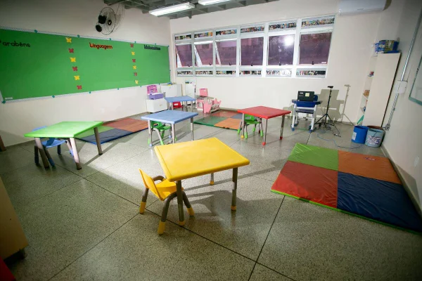 Sala de aula vazia com mesas coloridas