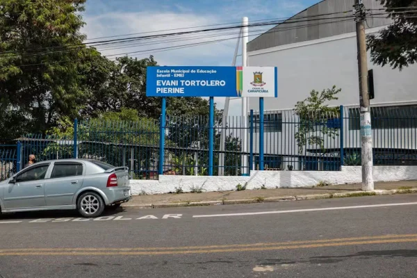 Imagem de fachada de escola, com portão e placa azuis - Metrópoles