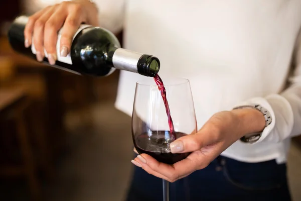 Foto de mulher colocando vinho dentro de uma taça - Metrópoles - álcool