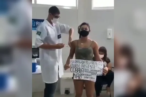 Após passaporte, mulher se vacina no Rio com cartaz “não à ditadura sanitária”
