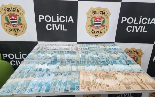 Imagem colorida de notas de R$50 e R$100 espalhadas sobre uma mesa; na parede, o emblema da Polícia Civil; valor foi roubado por uma jovem da sua bisavó - Metrópoles