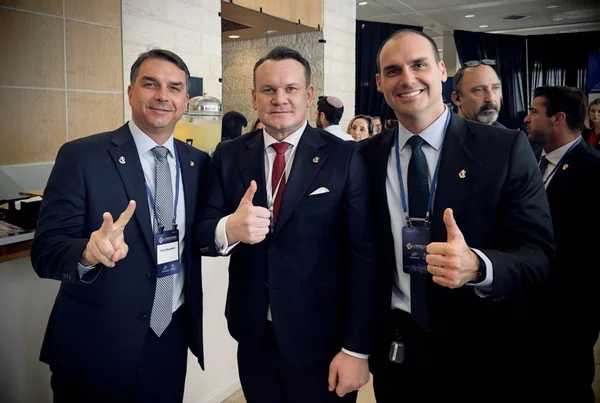 Imagem colorida mostra deputado polonês e Flavio Bolsonaro - Metrópoles
