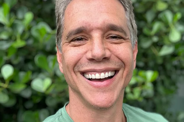 Márcio Garcia posa sorridente de camiseta verde - Metrópoles