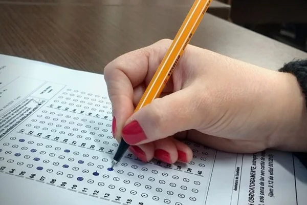 Mão de estudante preenchendo gabarito de prova de concurso - Metrópoles