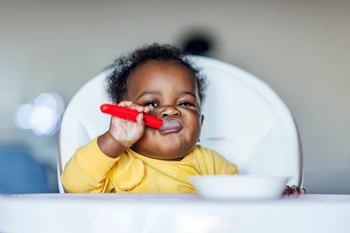 bebê com colher na boca comendo