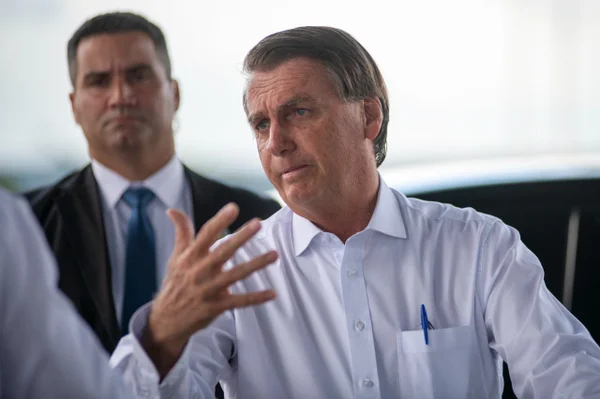 Bolsonaro fala com a imprensa antes da viagem para a Rússia, onde se encontra com o presidente Vladimir Putin. Ele aparece gesticulando, com um segurança e carro ao fundo - Metrópoles
