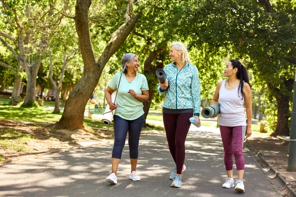 Três mulheres caminhando e conversando em parque - Metrópoles