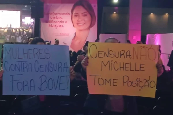 Fotografia colorida de duas mulheres levantando cartazes em evento do PL Mulher