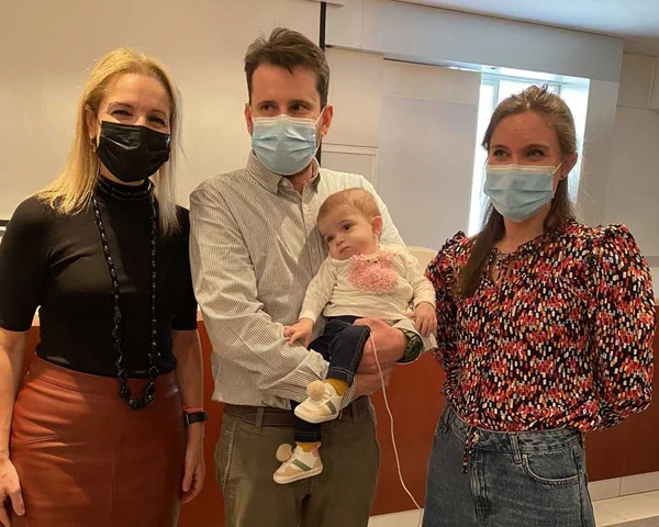 foto colorida de duas mulheres e homem segurando bebê no colo
