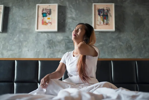 Imagem mostra mulher acordando com a mão nas costas, cansada - Metrópoles