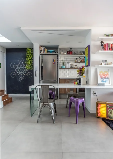 Os moradores queriam um layout aberto para a cozinha, com os utensílios à vista. O móvel da televisão se alonga, se tornando uma mesa de jantar que serve de bancada de apoio Os moradores queriam um layout aberto para a cozinha, com os utensílios à vista. O móvel da televisão se alonga, se tornando uma mesa de jantar que serve de bancada de apoio