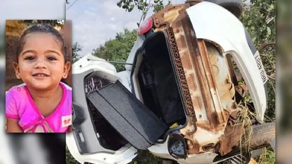 imagem colorida com uma criança pequena ao lado de um carro branco capotado - Metrópoles
