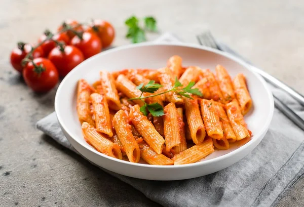 Macarrão em um prato de fundo branco com tomates - Metrópoles