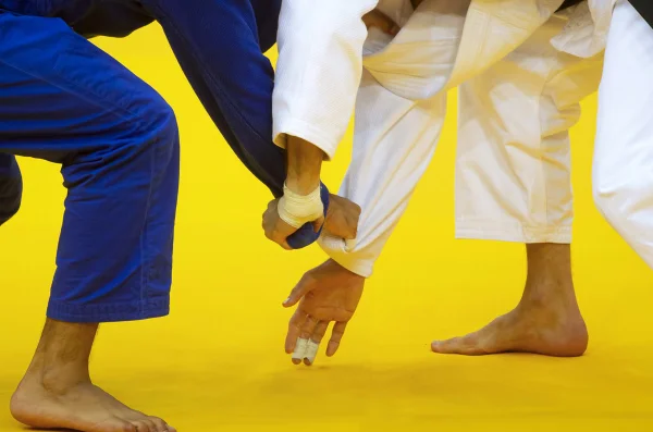 Imagem colorida de dois homens lutando com quimonos - Metrópoles