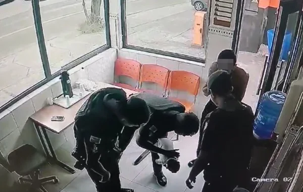 Imagem colorida mostra quatro policiais militares (PMs) em volta de um bebê recém nascido. Um deles está com ela no colo, dando "tapinhas" nas costas - Metrópoles