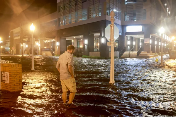 Brandon Marlow caminha através das ondas que inundam a rua depois que o furacão Milton atingiu a costa na área de Sarasota em 09 de outubro de 2024, em Fort Myers, Flórida
