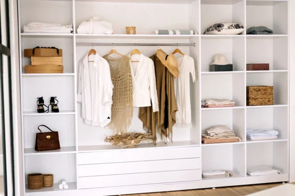 Guarda-roupa modulado branco com prateleiras e divisórias com algumas roupas dentro - Metrópoles