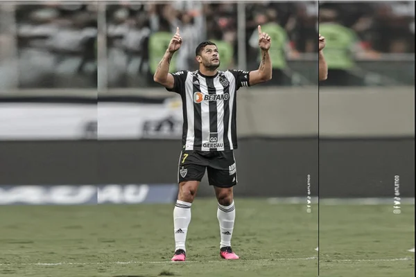 jogador com camisa preta e branca com os braços para cima