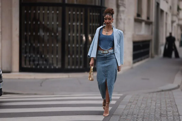 Mulher negra andando em faixa de pedestre na rua. Ela está segurando uma bolsa com a mão direita e usando acessório de cabeça - Metrópoles