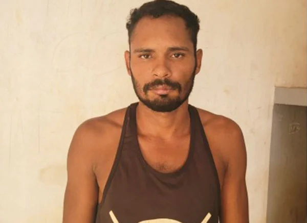 Fotografia de um homem pardo, adulto, magro, usando uma regata marrom