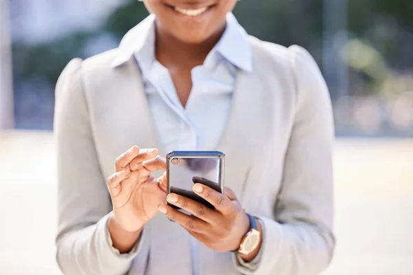 Foto desfocada de uma mulher andando na rua e sorrindo enquanto mexe no celular - Metrópoles