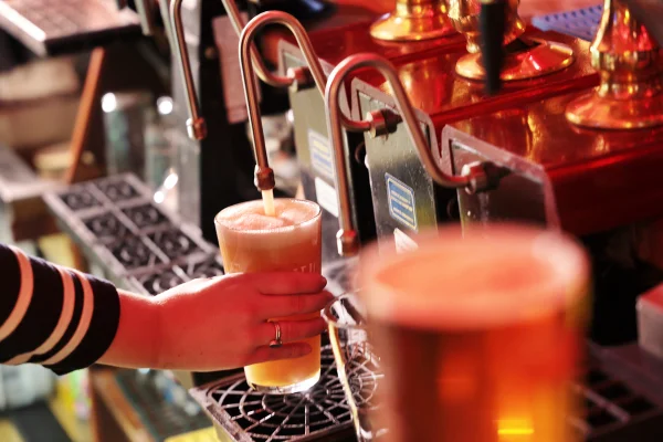 Foto colorida de mulher tirando cerveja de barril